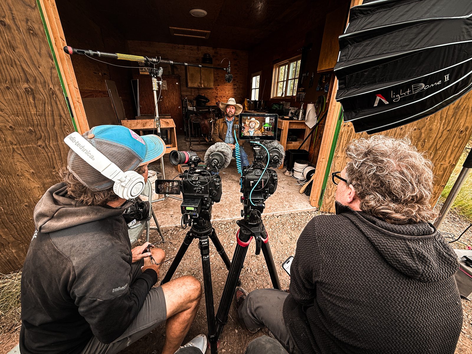 Film crew setting up a sit-down interview with a rancher inside a tack room